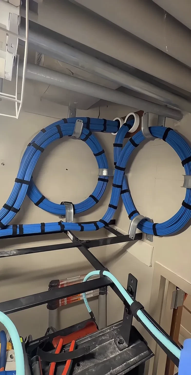 Neatly bundled Cat6 cable service loops coiled and secured to the wall before running down to the rack.